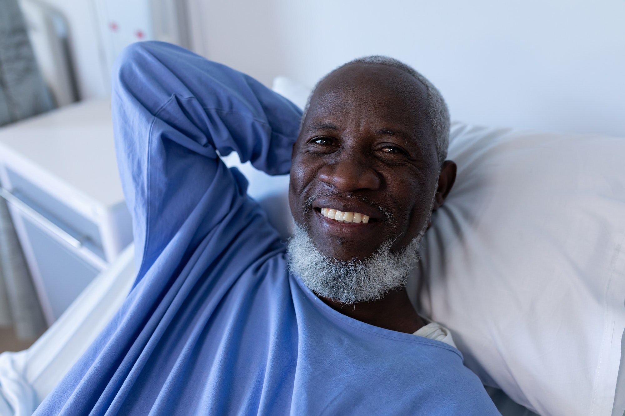 Portrait of african american male patient lying on hospital bed smiling to camera